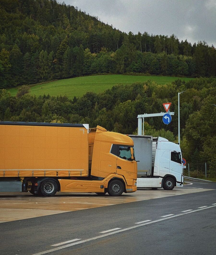 Yellow and white trucks parked at a scenic mountain rest stop under cloudy skies.